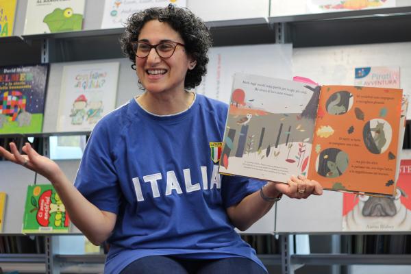 Woman in blue shirt holding picture book open. 