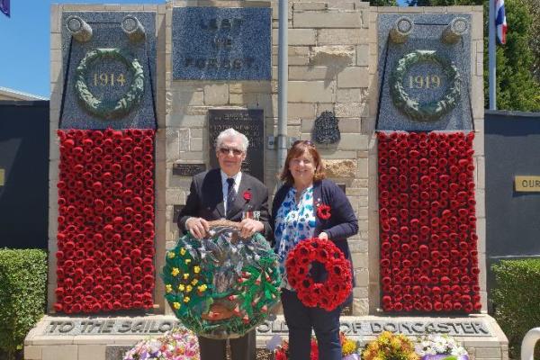 man and woman stand in front of Doncaster RSL war memorial holding wreaths