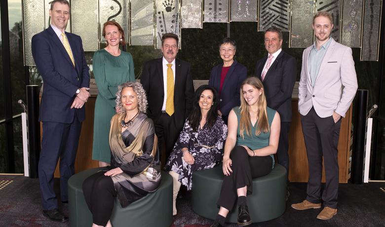 The nine 2022 Manningham Councillors, five standing and three sitting, all looking forwards smiling. 