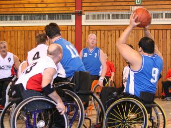 six men playing wheelchair basketball
